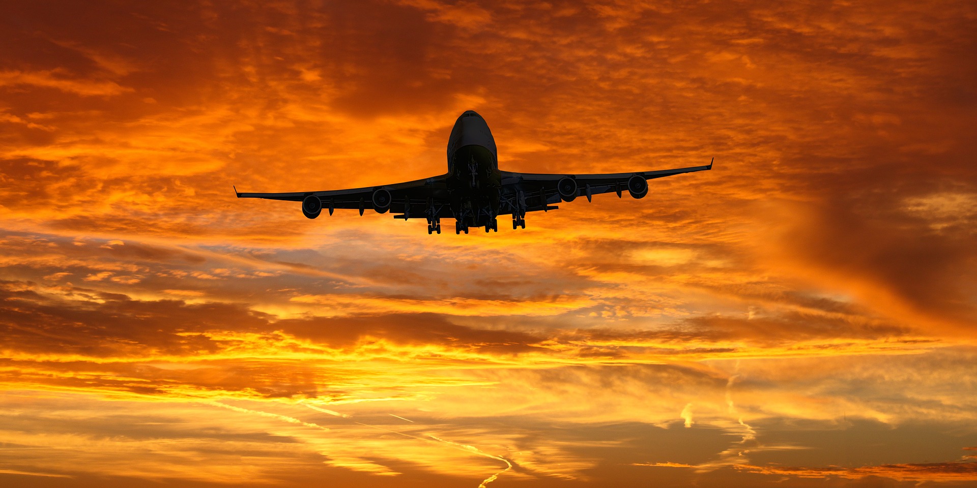 Plane flying in front of a bright orange sunset